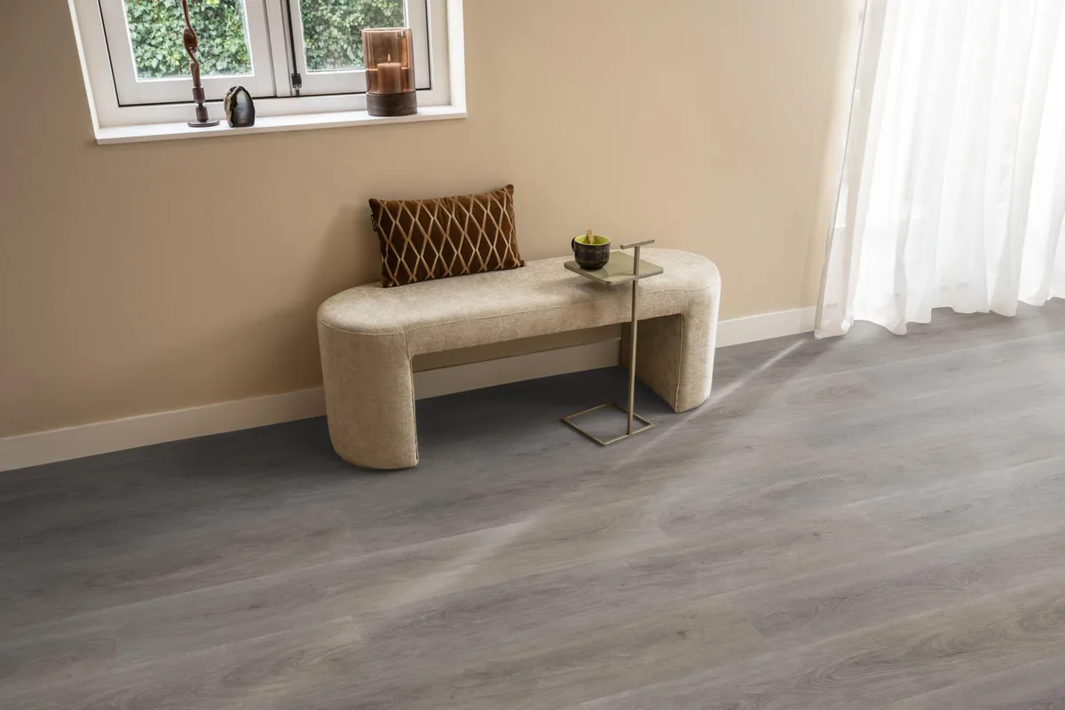 Parramatta / Robusto Grey oak, klik pvc in een hal, met een bankje onder het raam en zonlicht over de vloer