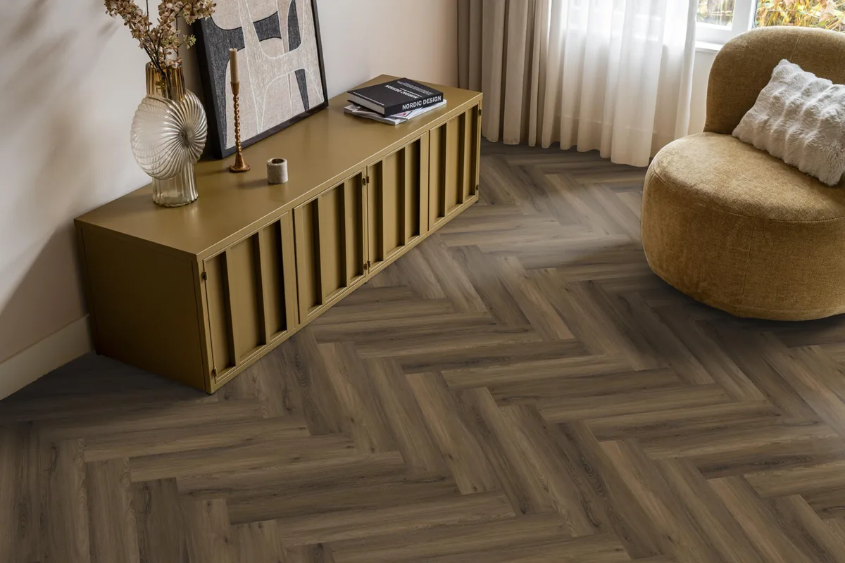 YUP / Spigato Warm brown, visgraat klik pvc in een woonkamer, met een okergeel dressoir en een ronde fauteuil