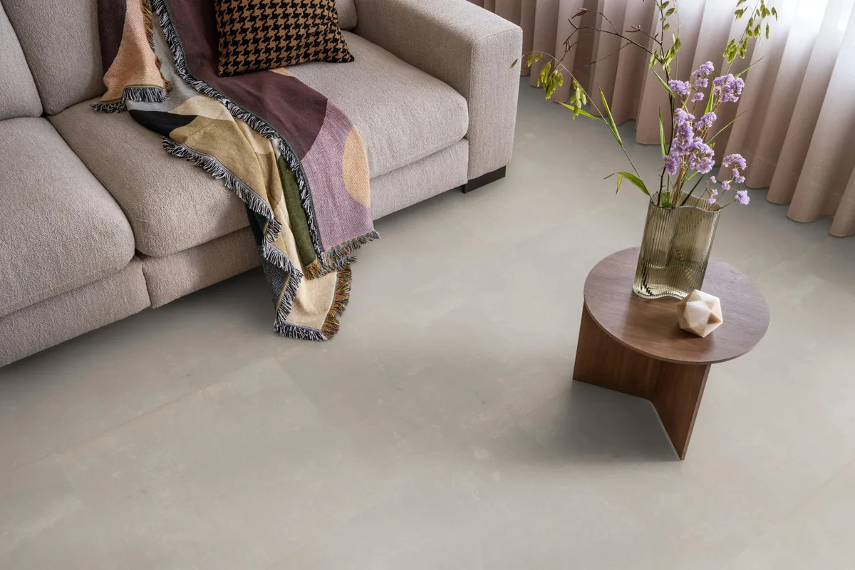 Westminster / Piero beige, klik pvc in een woonkamer, met een beige bank en een ronde bijzettafel met bloemen