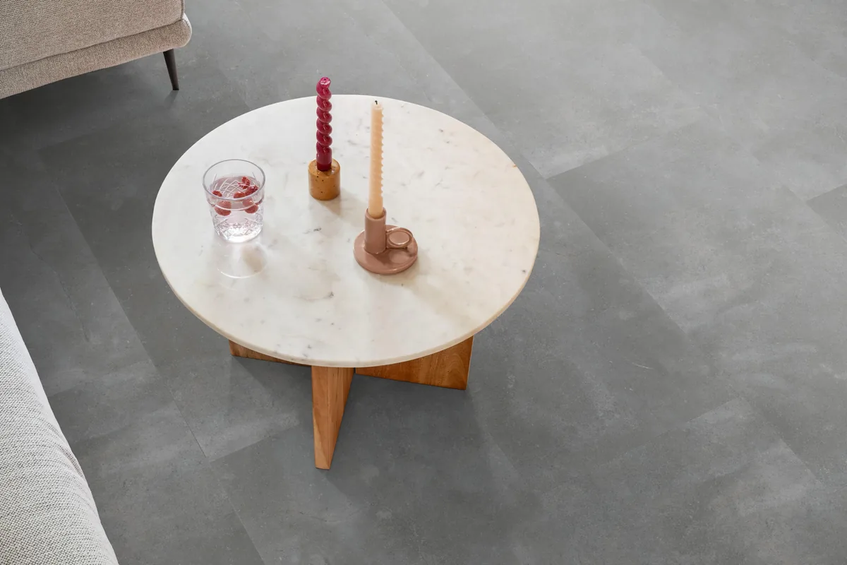 Ealing / Piazzo grey, klik pvc in een woonkamer, met een ronde marmeren salontafel en twee kaarsen