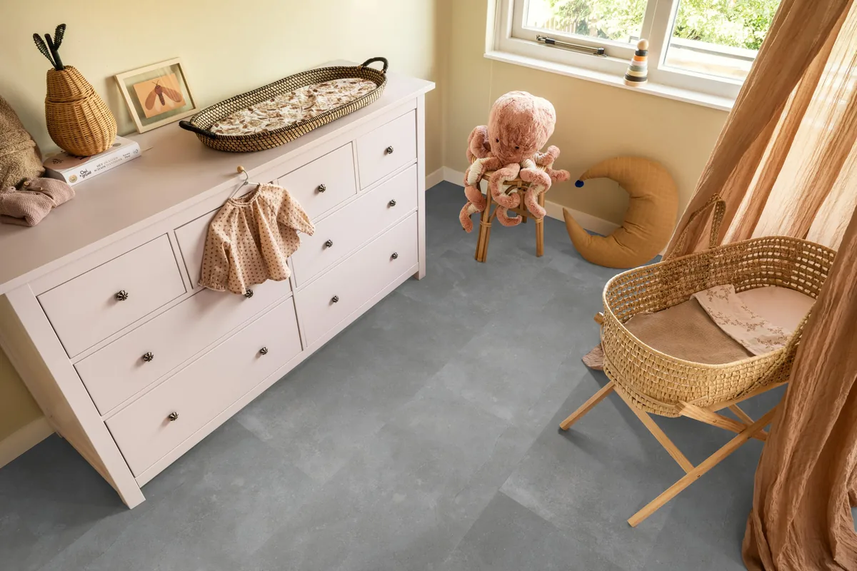 Ealing / Piazzo grey, klik pvc in een babykamer, met een witte commode en een rieten wieg