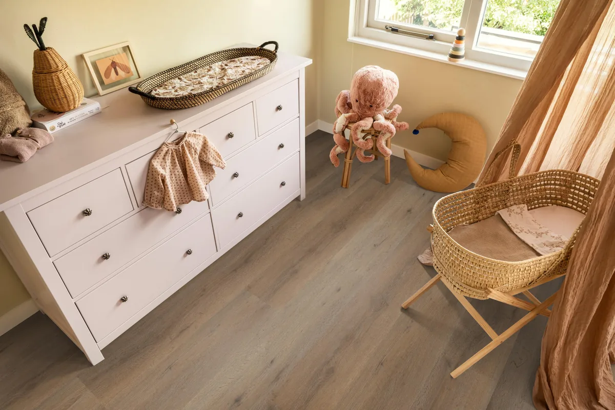 Leyton / Vivero smoky, klik pvc in een babykamer, met een witte commode en een rieten wieg