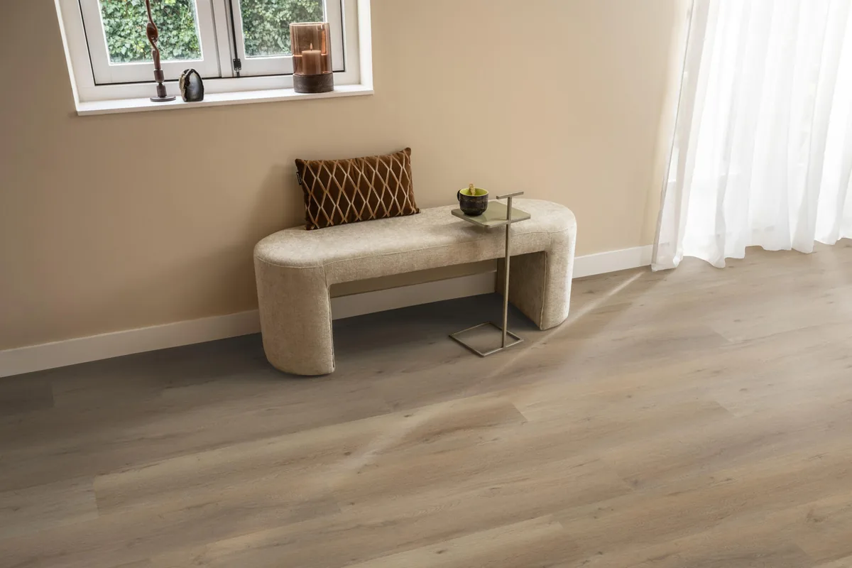 Leyton / Vivero natural oak, klik pvc in een hal, met een bankje onder het raam en zonlicht over de vloer