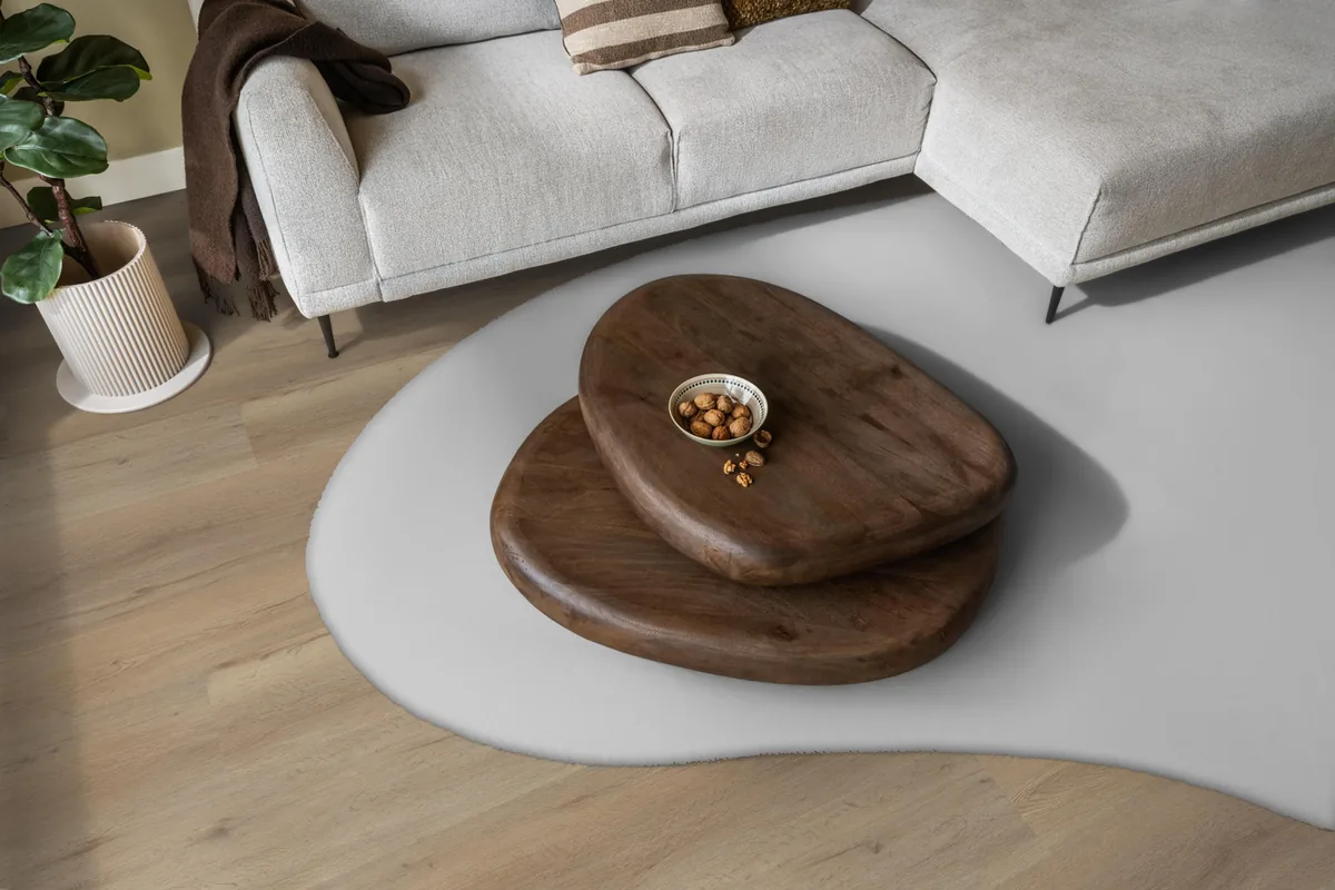 Leyton / Vivero natural oak, klik pvc in een woonkamer, met een lichte hoekbank en een wit vloerkleed