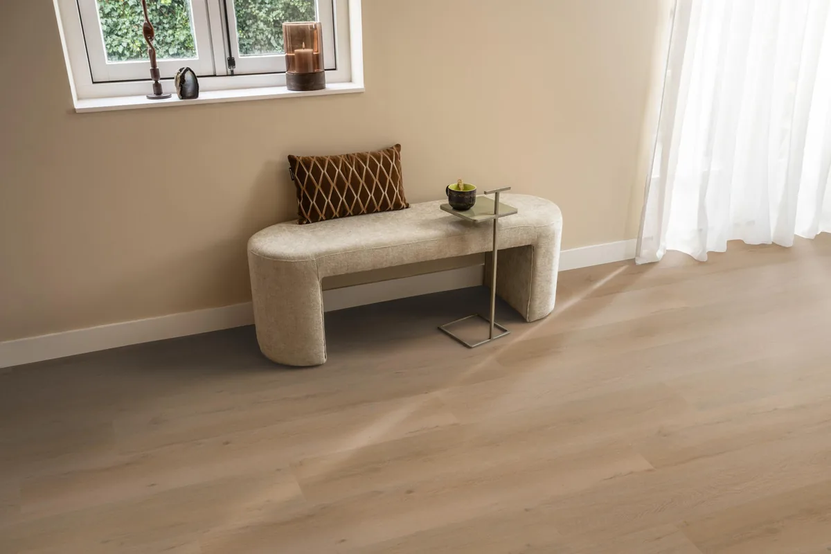 Leyton / Vivero warm oak, klik pvc in een hal, met een bankje onder het raam en zonlicht over de vloer