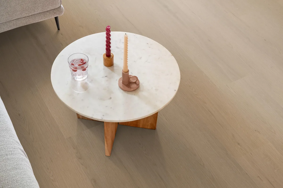 Barnet / Venera natural oak, plak pvc in een woonkamer, met een ronde marmeren salontafel en twee kaarsen