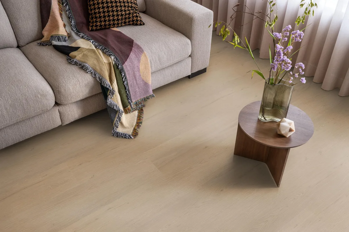 Barnet / Venera natural oak, plak pvc in een woonkamer, met een beige bank en een ronde bijzettafel met bloemen