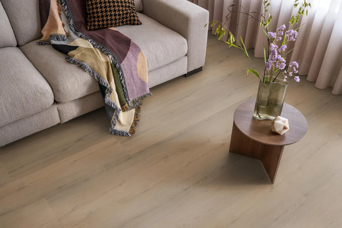 Barnet / Venera Dark oak, klik pvc in een woonkamer, met een beige bank en een ronde bijzettafel met bloemen