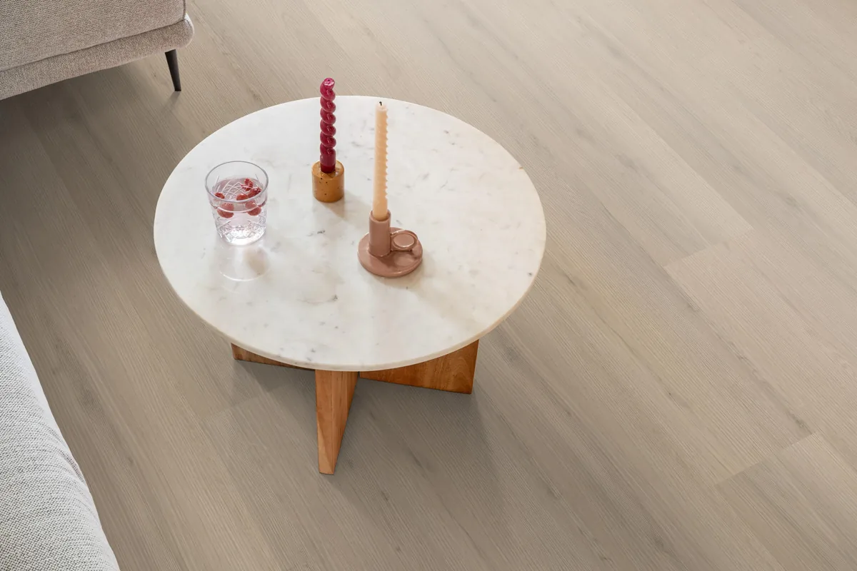 Barnet / Venera Beige, klik pvc in een woonkamer, met een ronde marmeren salontafel en twee kaarsen