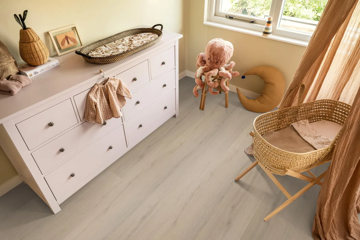 Barnet / Venera Beige, klik pvc in een babykamer, met een witte commode en een rieten wieg