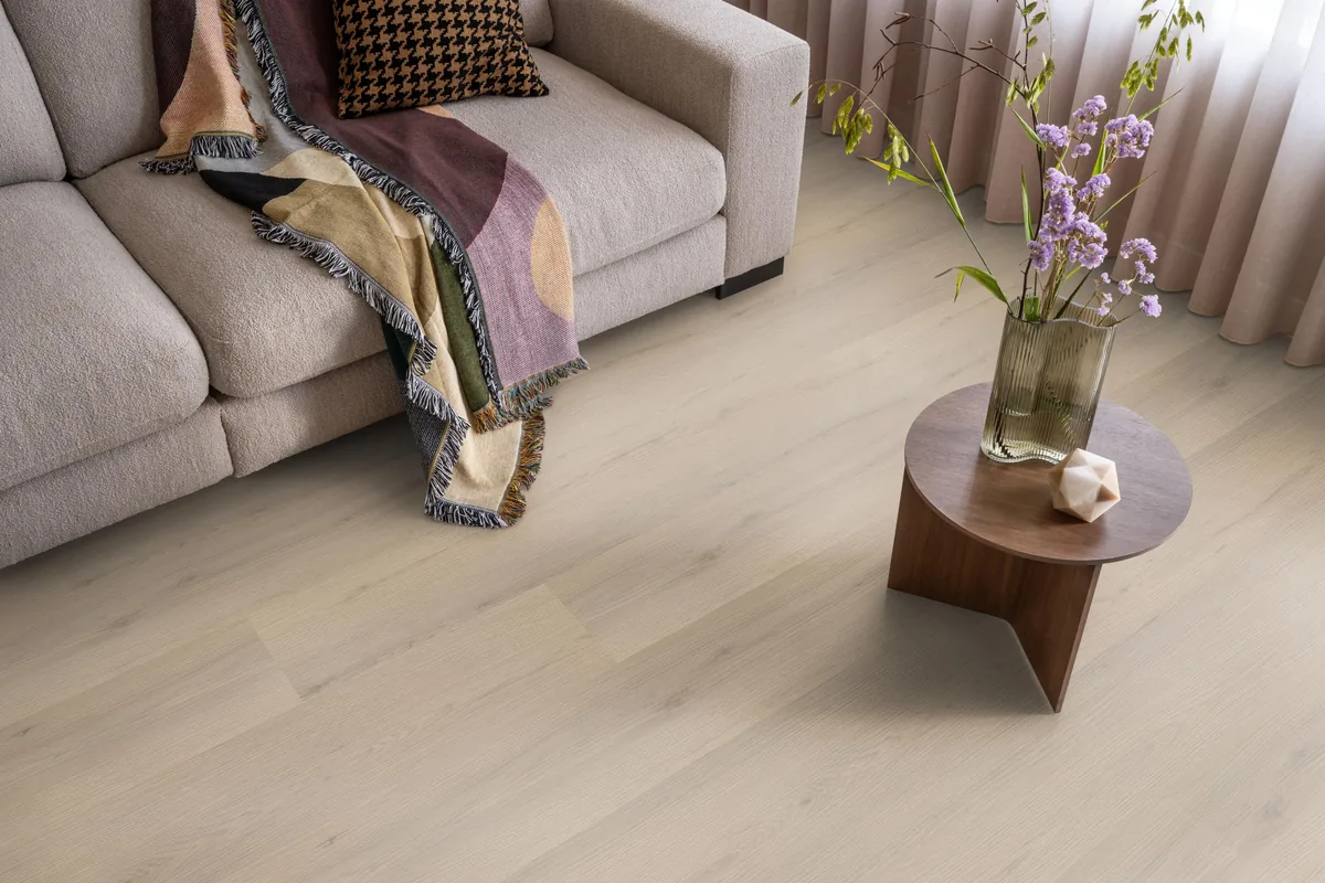 Barnet / Venera Beige, klik pvc in een woonkamer, met een beige bank en een ronde bijzettafel met bloemen