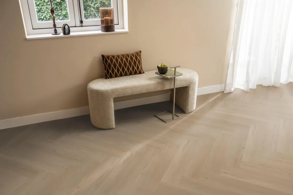 Leyton / Vivero beige, visgraat plak pvc in een hal, met een bankje onder het raam en zonlicht over de vloer