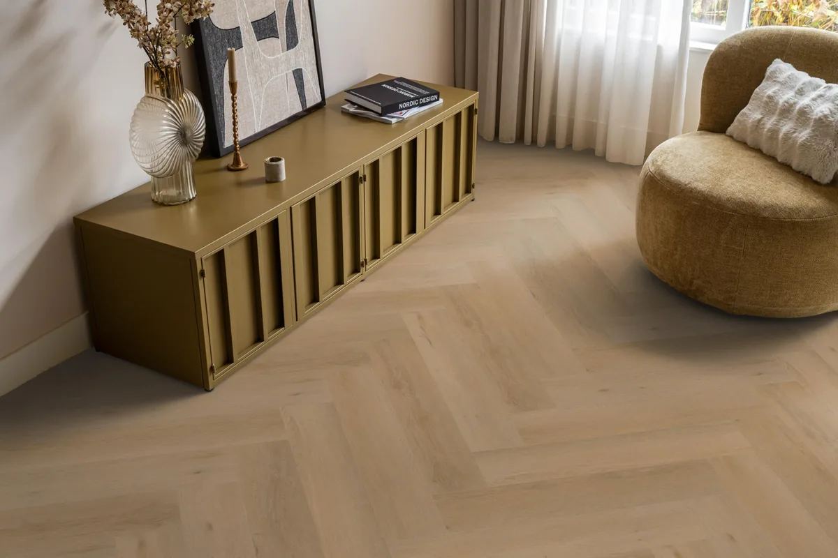 Leyton / Vivero warm oak, visgraat plak pvc in een woonkamer, met een okergeel dressoir en een ronde fauteuil