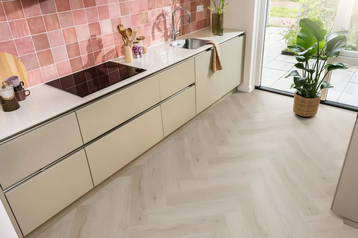 Leyton / Vivero Light oak, visgraat klik pvc in een keuken met een roze tegelwand en openslaande tuindeuren