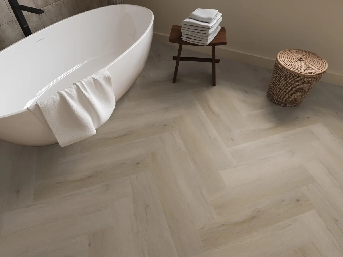 Leyton / Vivero Light oak, visgraat klik pvc in een badkamer, met een vrijstaand bad en een rieten wasmand