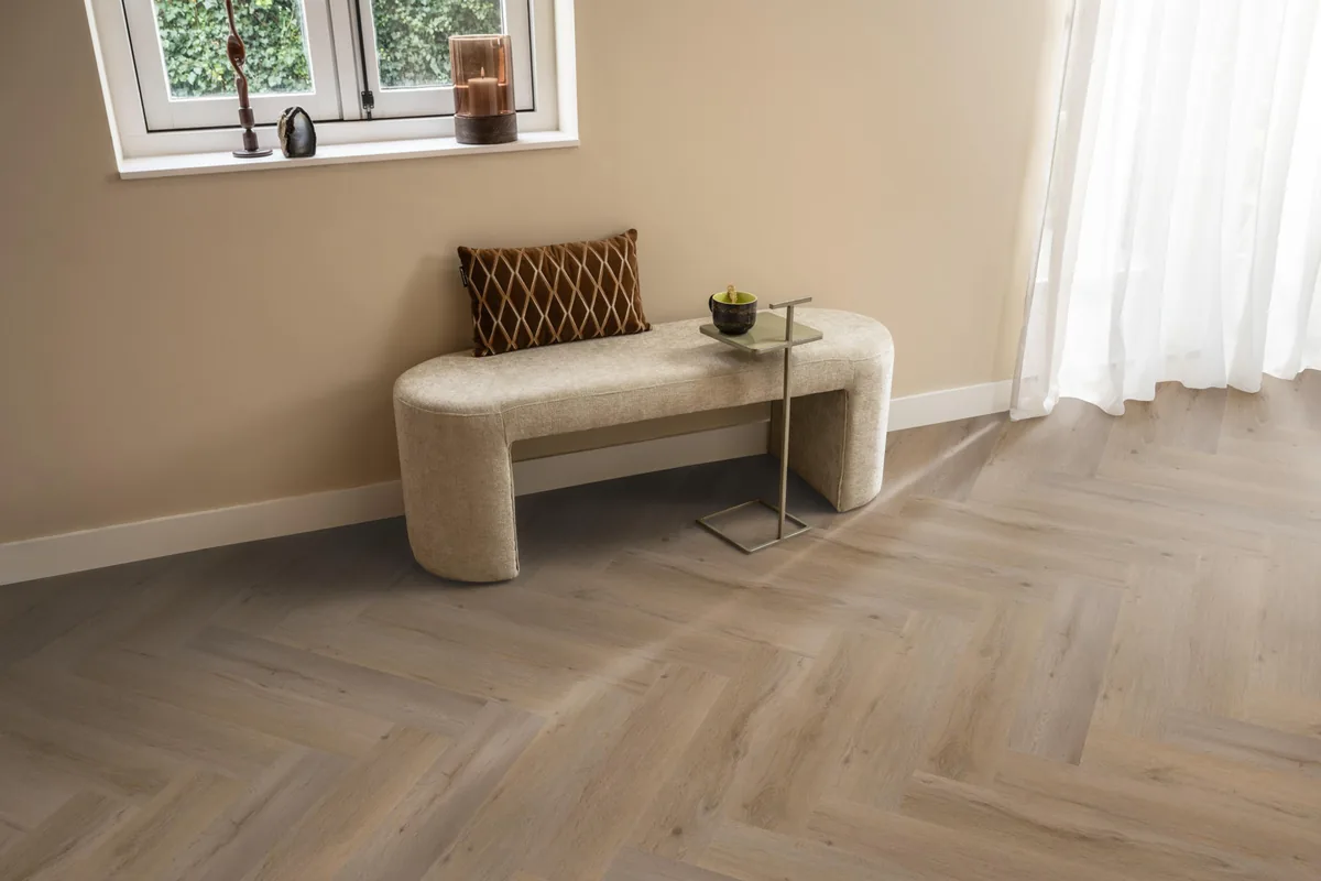Leyton / Vivero Smoky, visgraat klik pvc in een hal, met een bankje onder het raam en zonlicht over de vloer