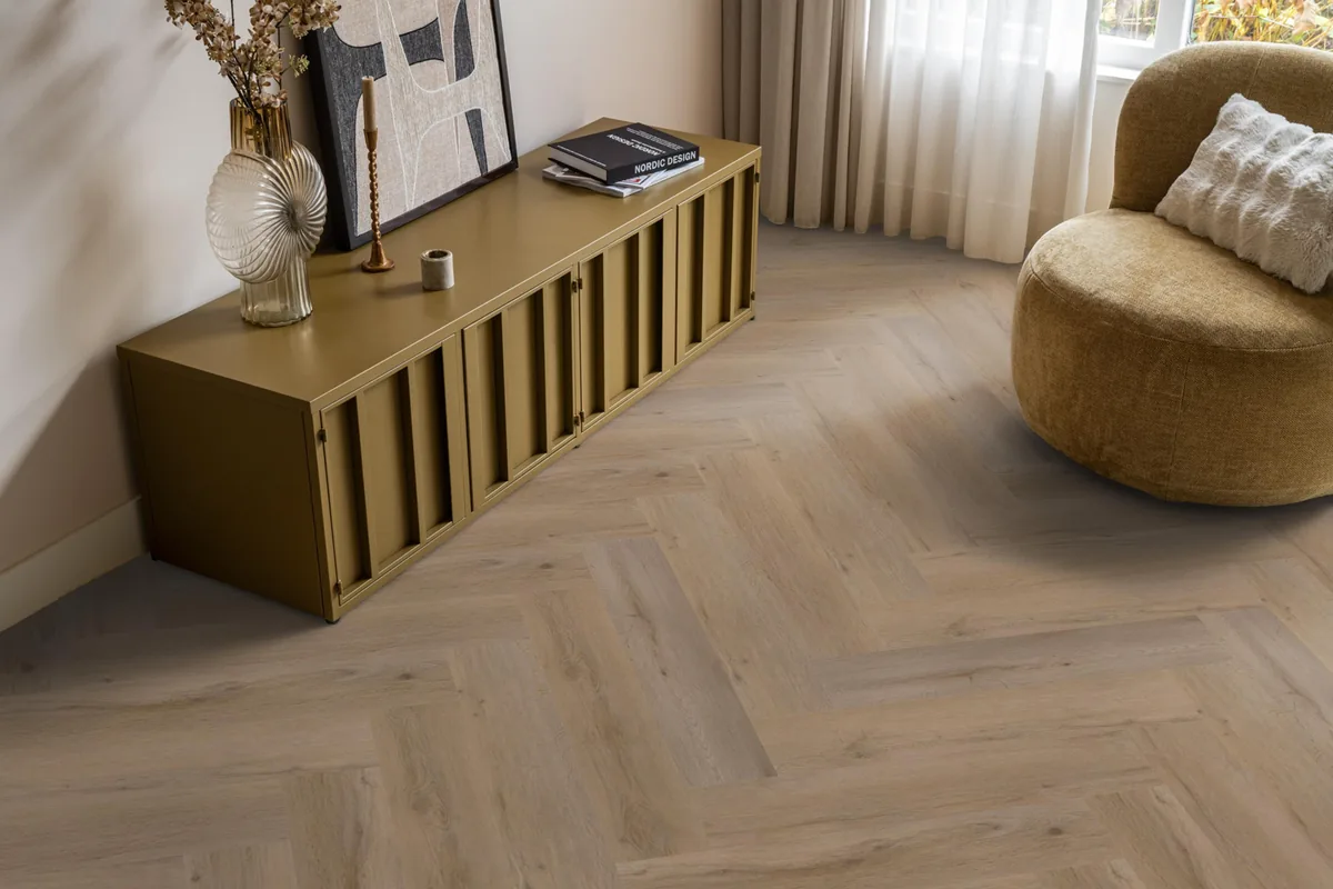 Leyton / Vivero Smoky, visgraat klik pvc in een woonkamer, met een okergeel dressoir en een ronde fauteuil