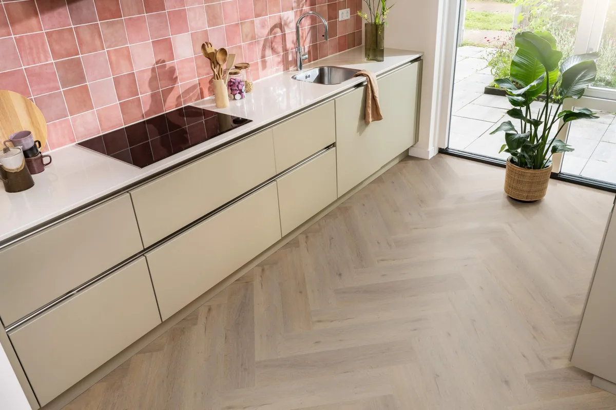 Leyton / Vivero Natural oak, visgraat klik pvc in een keuken met een roze tegelwand en openslaande tuindeuren