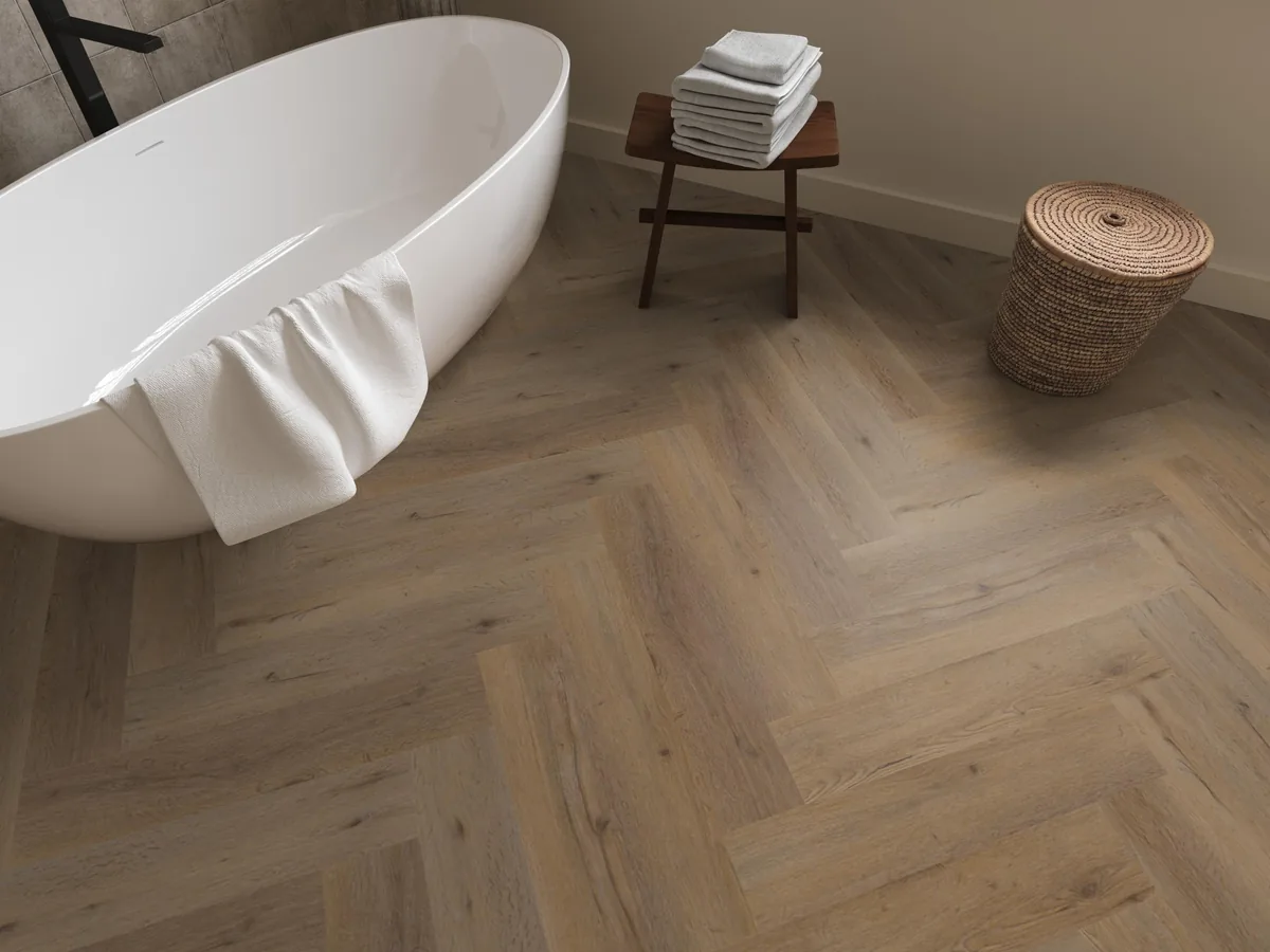 Leyton / Vivero Natural oak, visgraat klik pvc in een badkamer, met een vrijstaand bad en een rieten wasmand