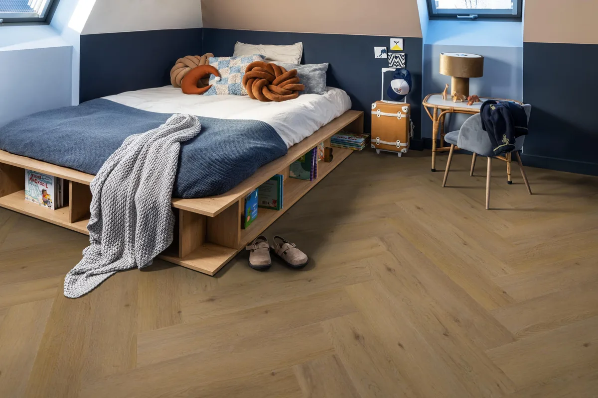 Leyton / Vivero Dark oak, visgraat klik pvc in een slaapkamer onder een schuin dak, met een houten bedombouw en sloffen ervoor