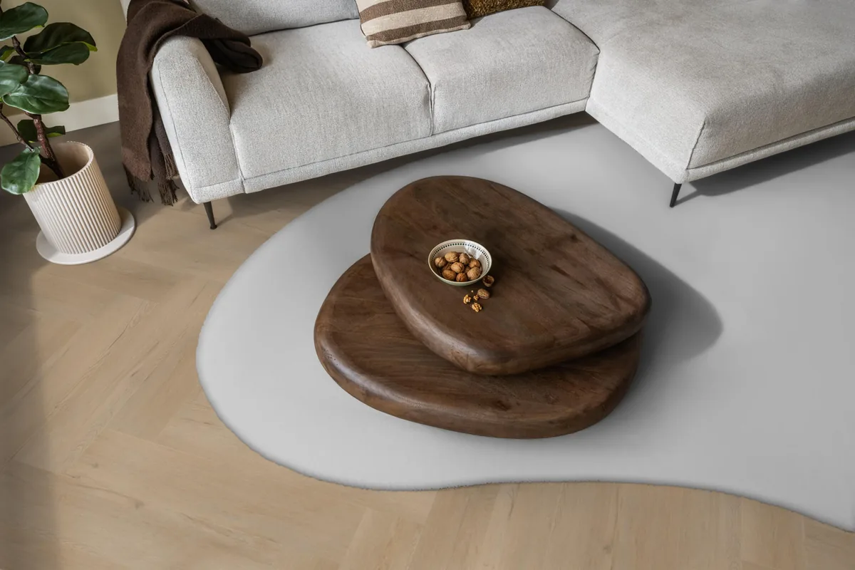 Leyton / Vivero Beige, visgraat klik pvc in een woonkamer, met een lichte hoekbank en een wit vloerkleed