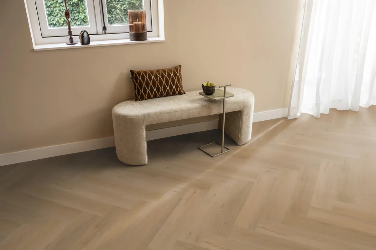 Leyton / Vivero Warm oak, visgraat klik pvc in een hal, met een bankje onder het raam en zonlicht over de vloer
