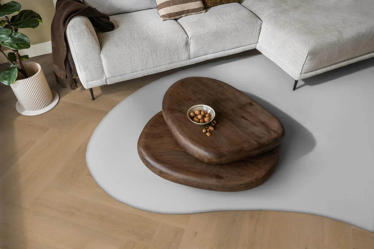 Leyton / Vivero Warm oak, visgraat klik pvc in een woonkamer, met een lichte hoekbank en een wit vloerkleed