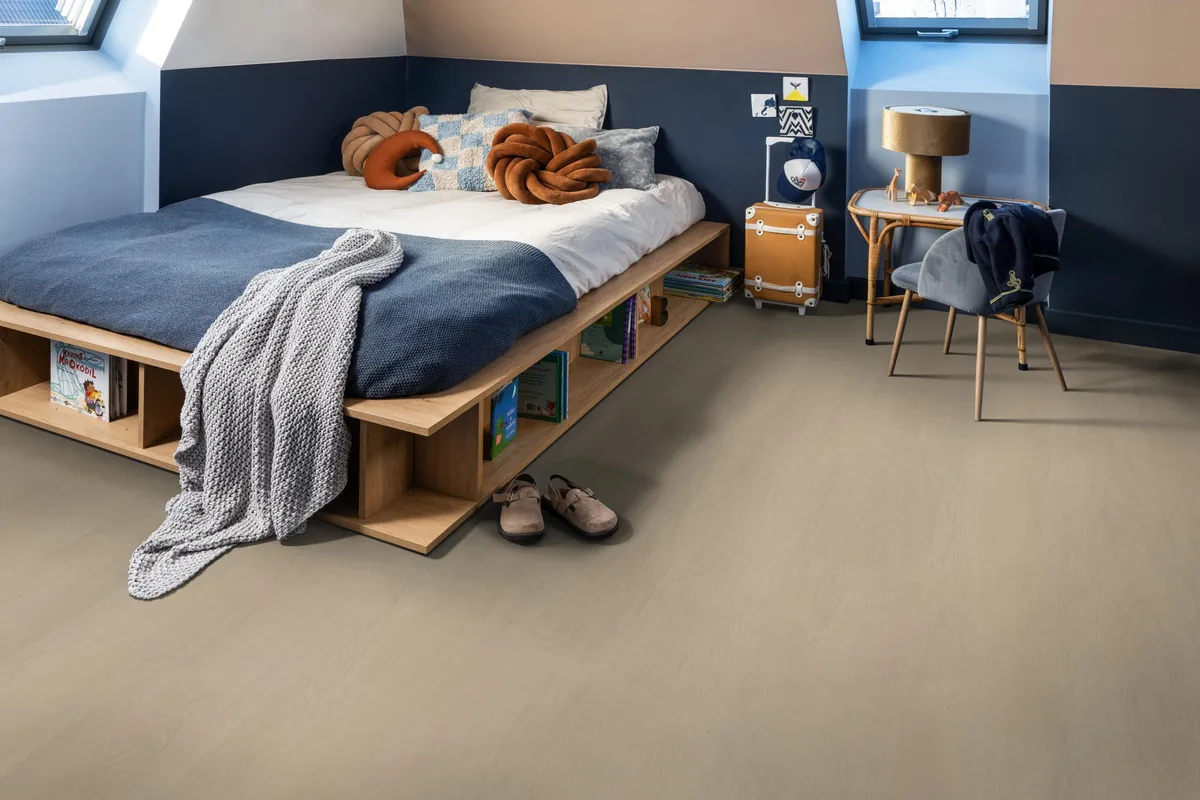 Fulham / Estino beige, plak pvc in een slaapkamer onder een schuin dak, met een houten bedombouw en sloffen ervoor