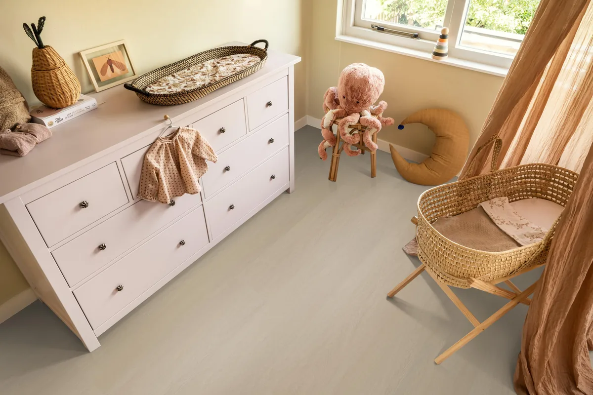 Fulham / Estino beige, plak pvc in een babykamer, met een witte commode en een rieten wieg