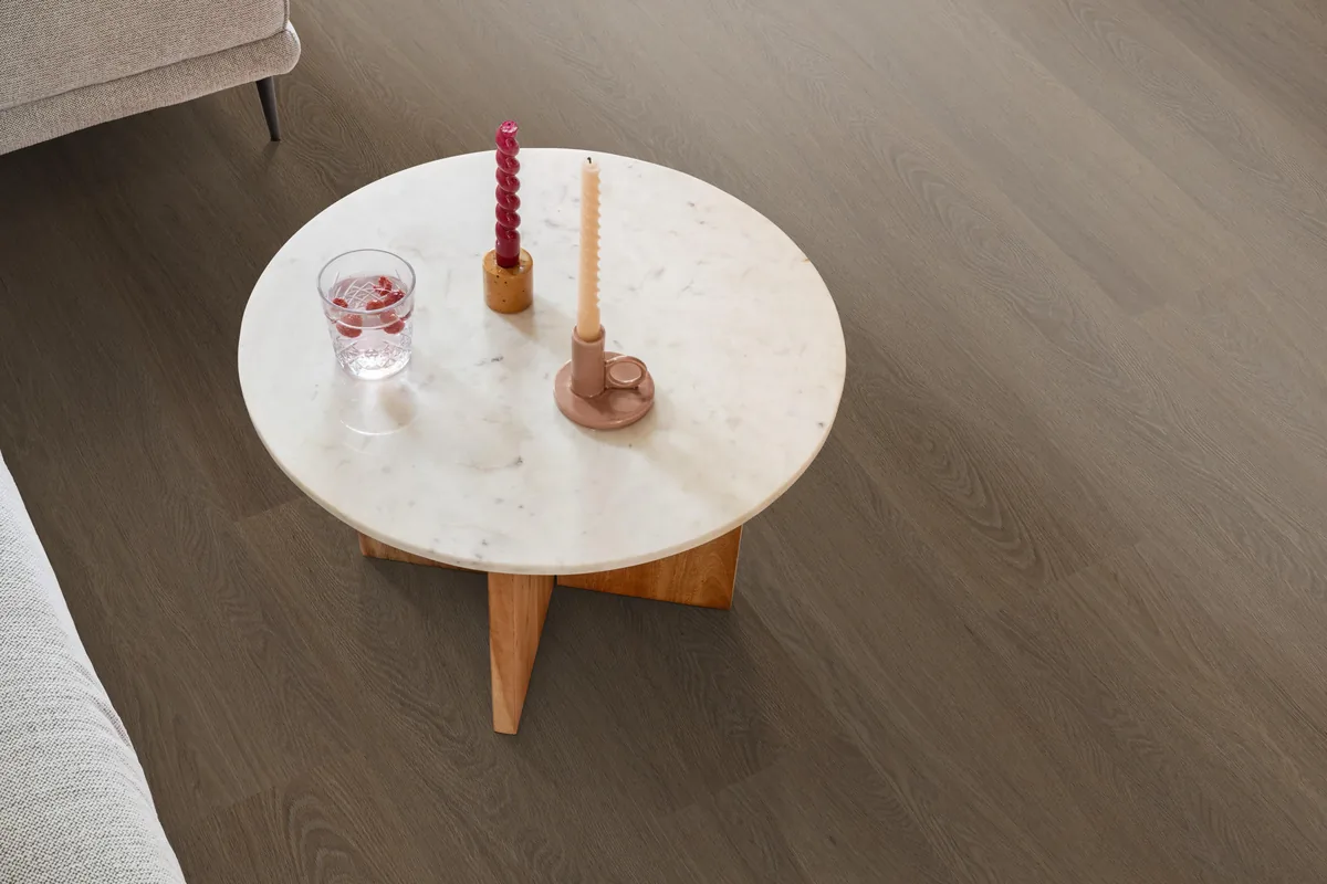 Fulham / Estino brown, plak pvc in een woonkamer, met een ronde marmeren salontafel en twee kaarsen