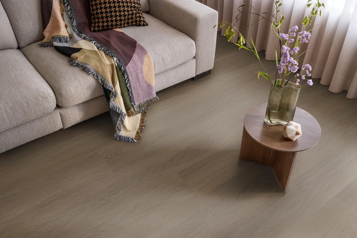 Fulham / Estino brown, plak pvc in een woonkamer, met een beige bank en een ronde bijzettafel met bloemen