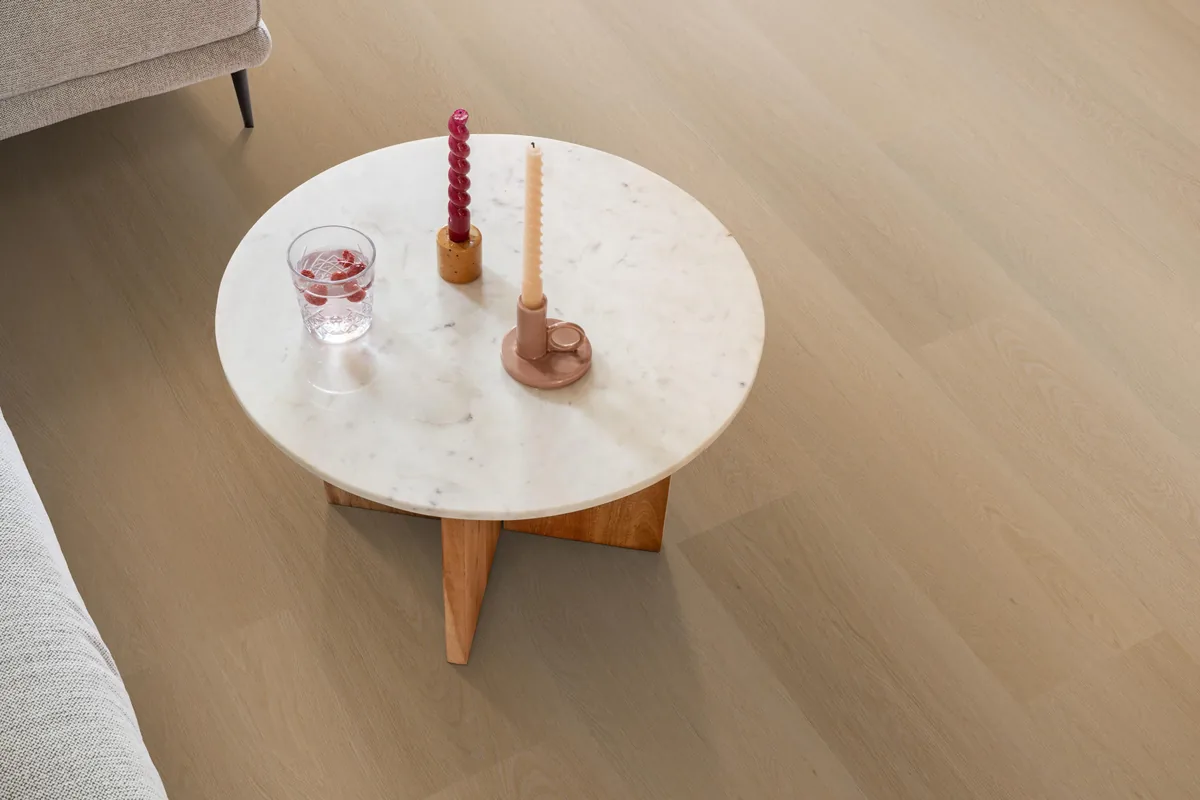 Fulham / Estino dark oak, klik pvc in een woonkamer, met een ronde marmeren salontafel en twee kaarsen