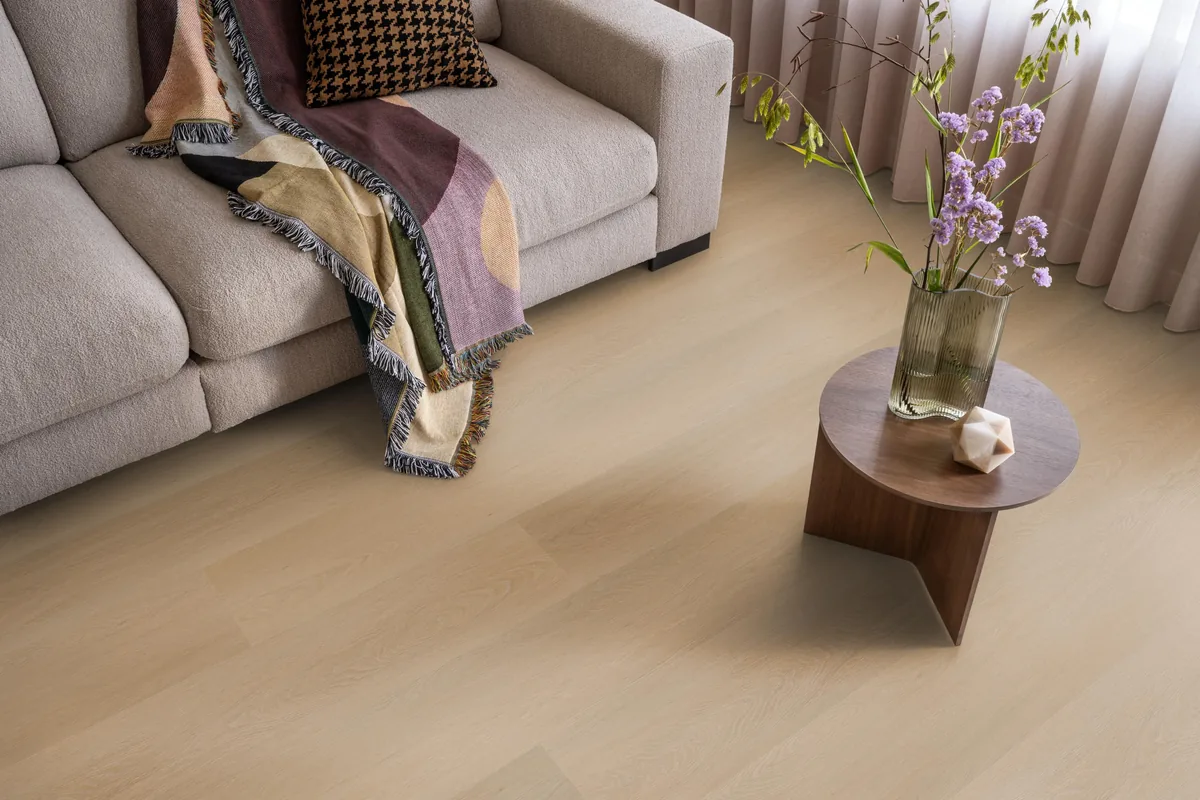 Fulham / Estino dark oak, klik pvc in een woonkamer, met een beige bank en een ronde bijzettafel met bloemen