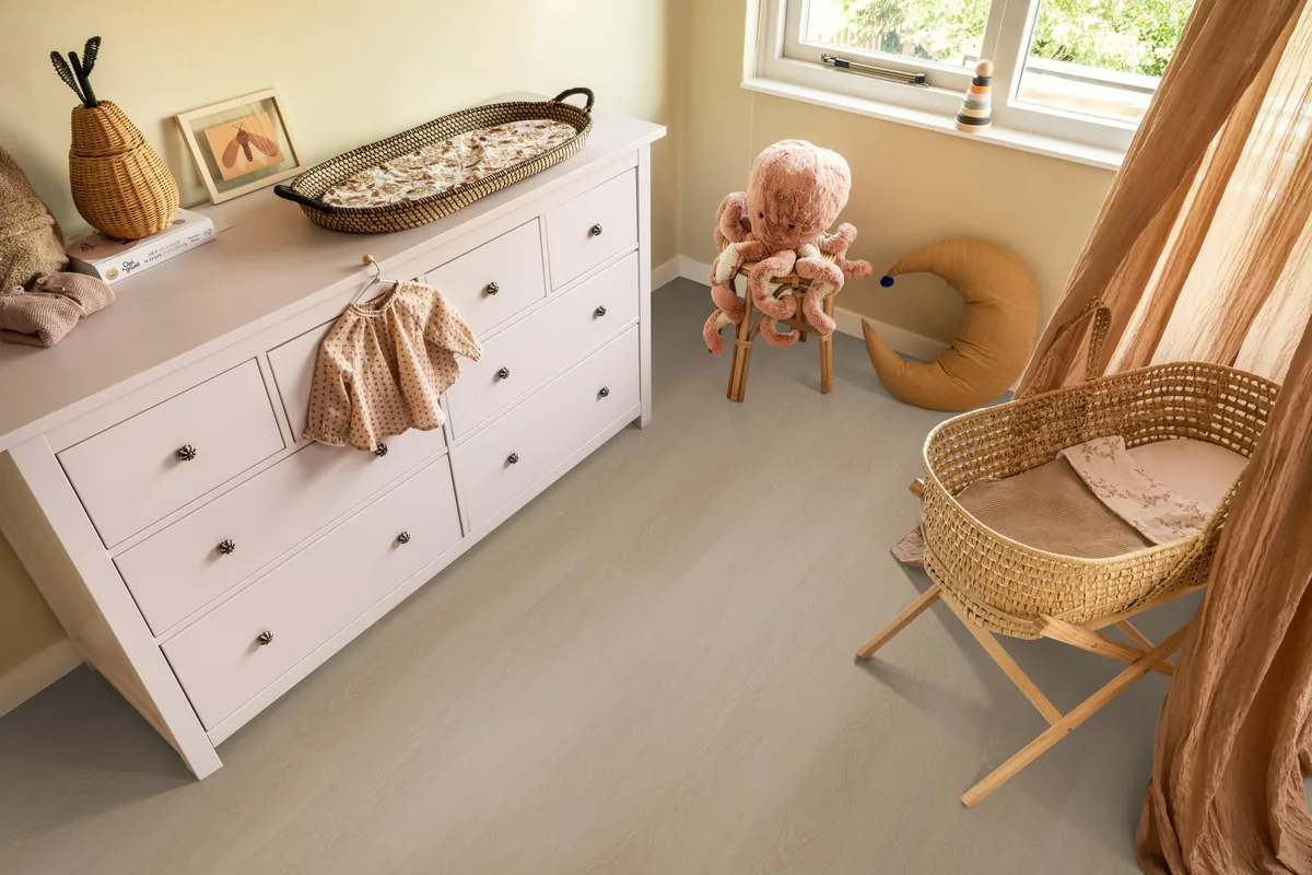 Fulham / Estino smoky, klik pvc in een babykamer, met een witte commode en een rieten wieg