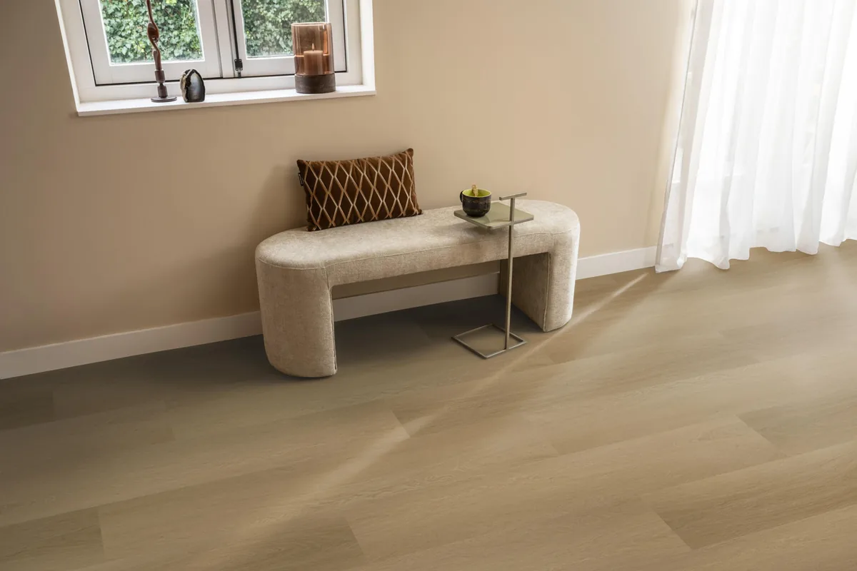 Fulham / Estino warm oak, klik pvc in een hal, met een bankje onder het raam en zonlicht over de vloer