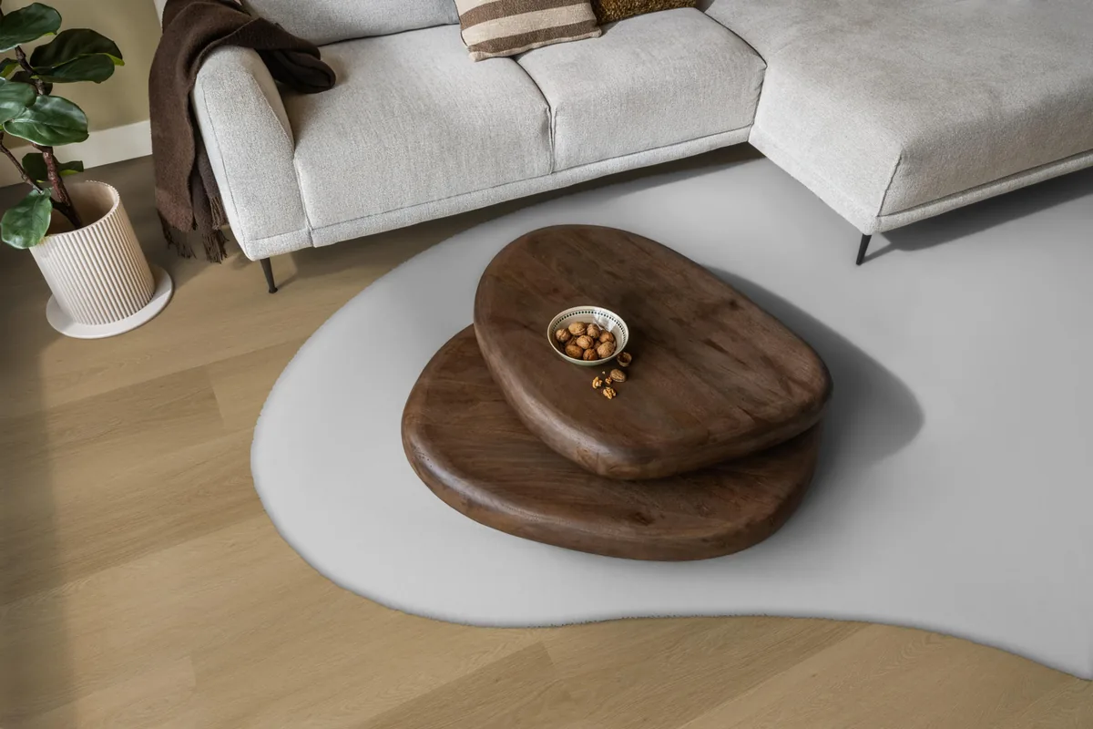 Fulham / Estino warm oak, klik pvc in een woonkamer, met een lichte hoekbank en een wit vloerkleed