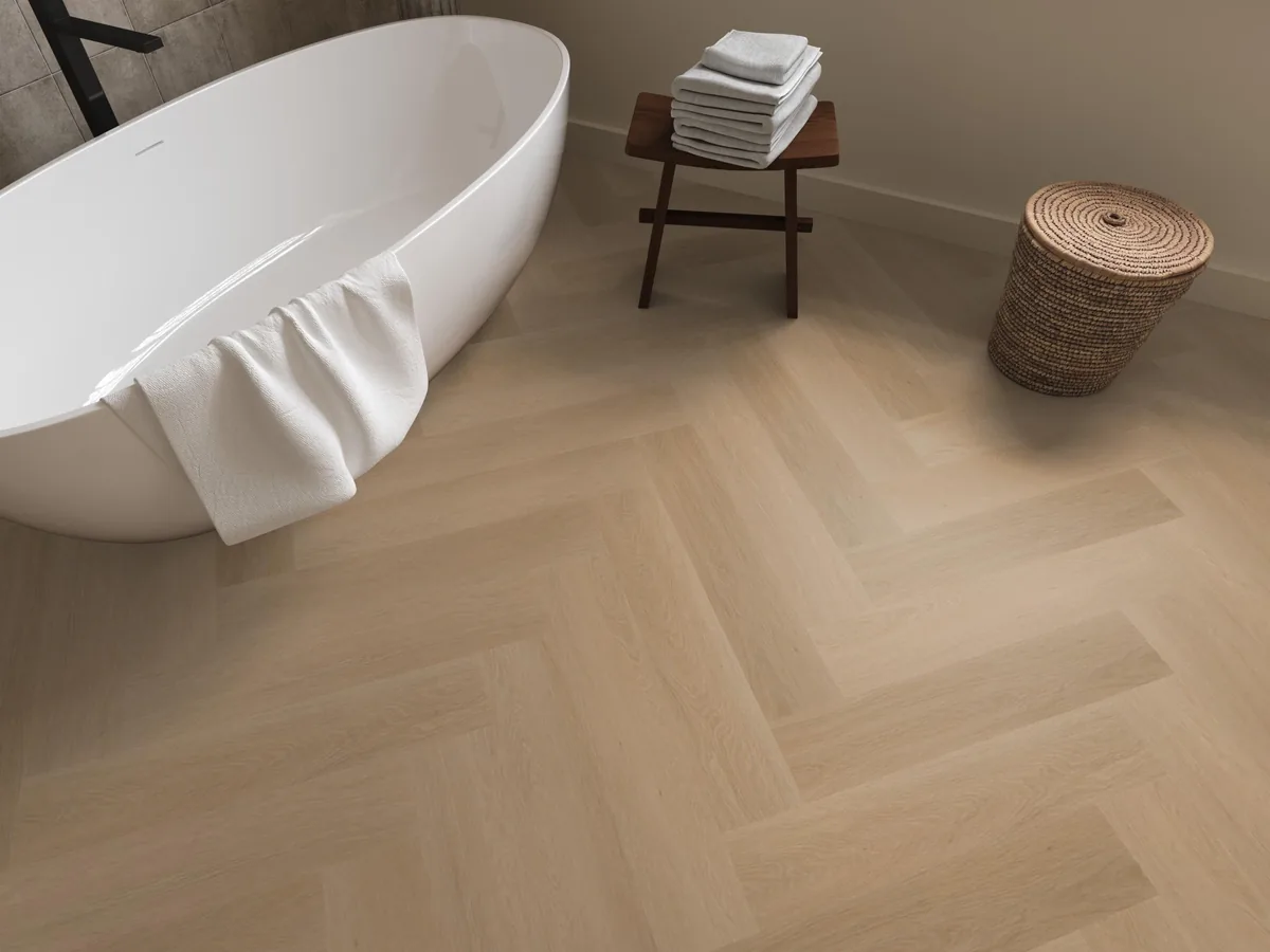 Fulham / Estino dark oak, visgraat plak pvc in een badkamer, met een vrijstaand bad en een rieten wasmand