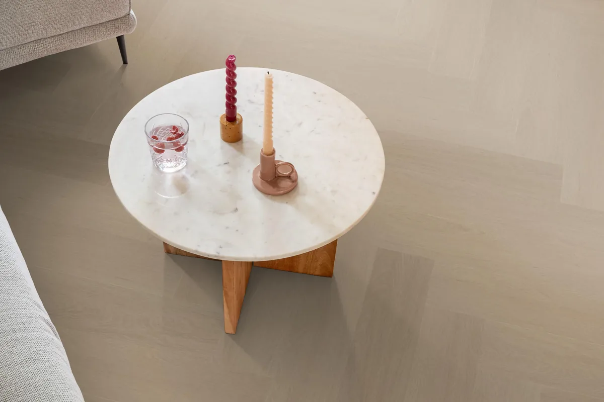 Fulham / Estino smoky, visgraat plak pvc in een woonkamer, met een ronde marmeren salontafel en twee kaarsen