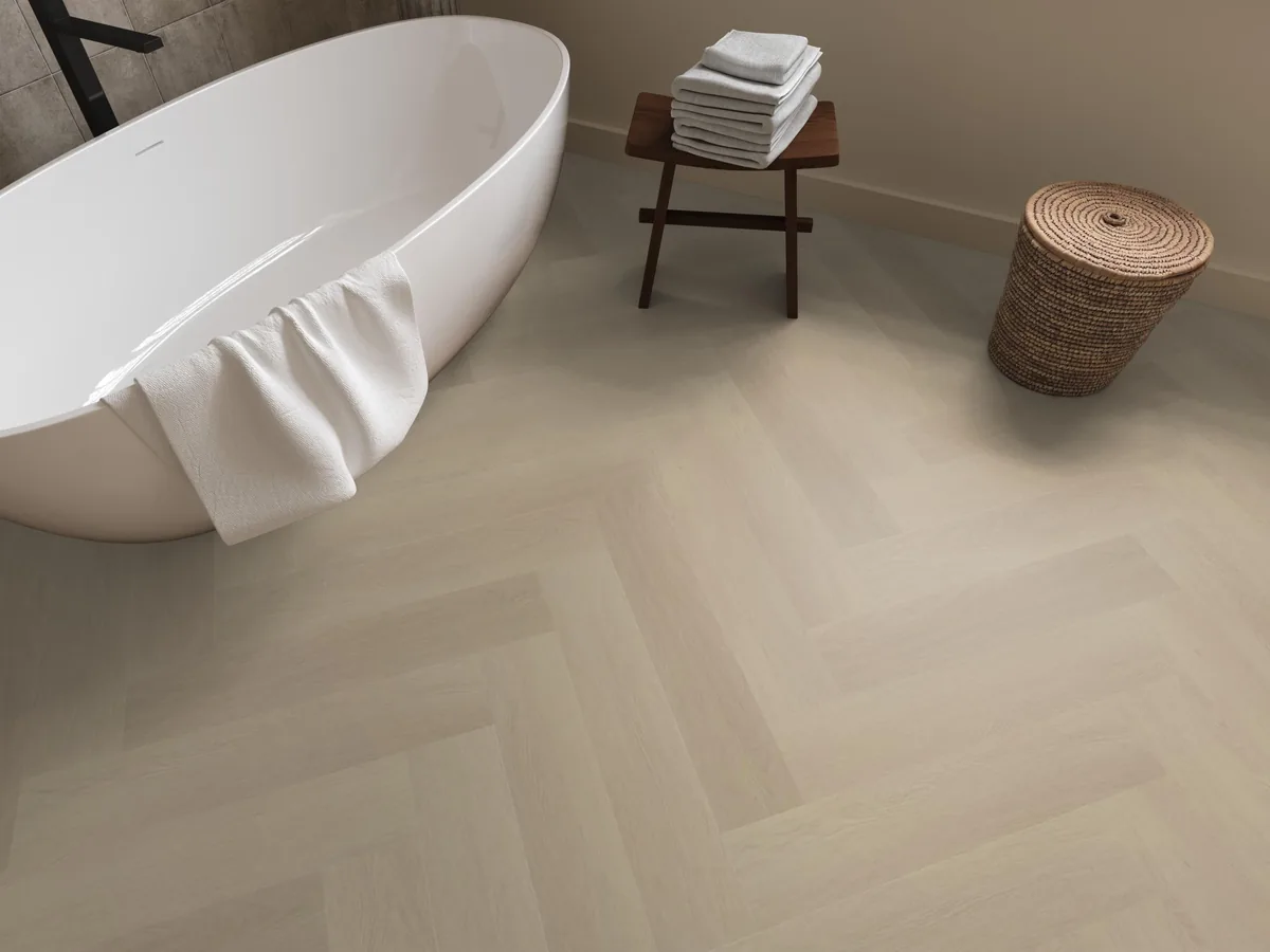 Fulham / Estino beige, visgraat plak pvc in een badkamer, met een vrijstaand bad en een rieten wasmand