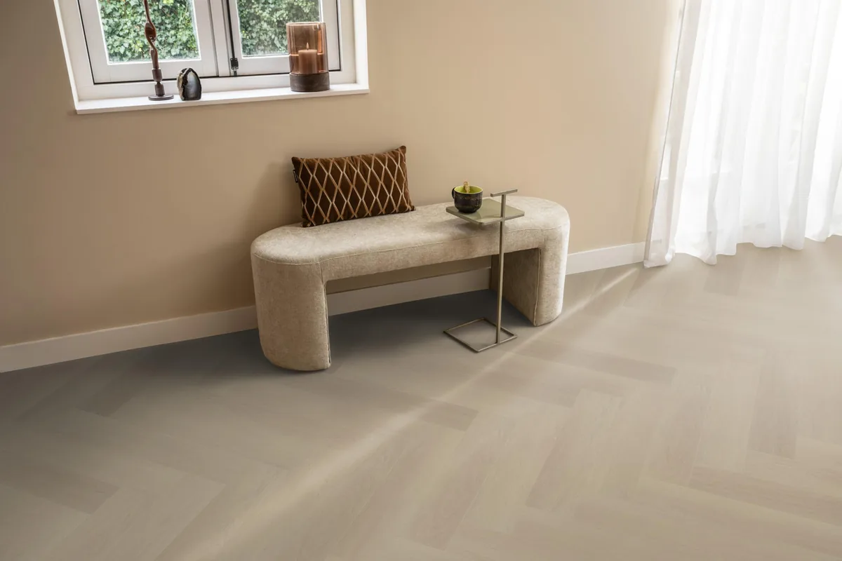 Fulham / Estino beige, visgraat plak pvc in een hal, met een bankje onder het raam en zonlicht over de vloer