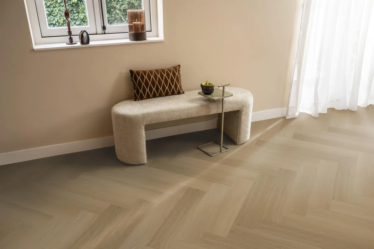 Fulham / Estino warm oak, visgraat plak pvc in een hal, met een bankje onder het raam en zonlicht over de vloer