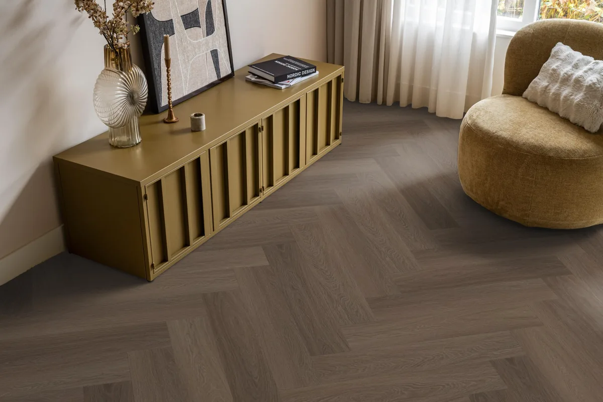 Fulham / Estino brown, visgraat plak pvc in een woonkamer, met een okergeel dressoir en een ronde fauteuil