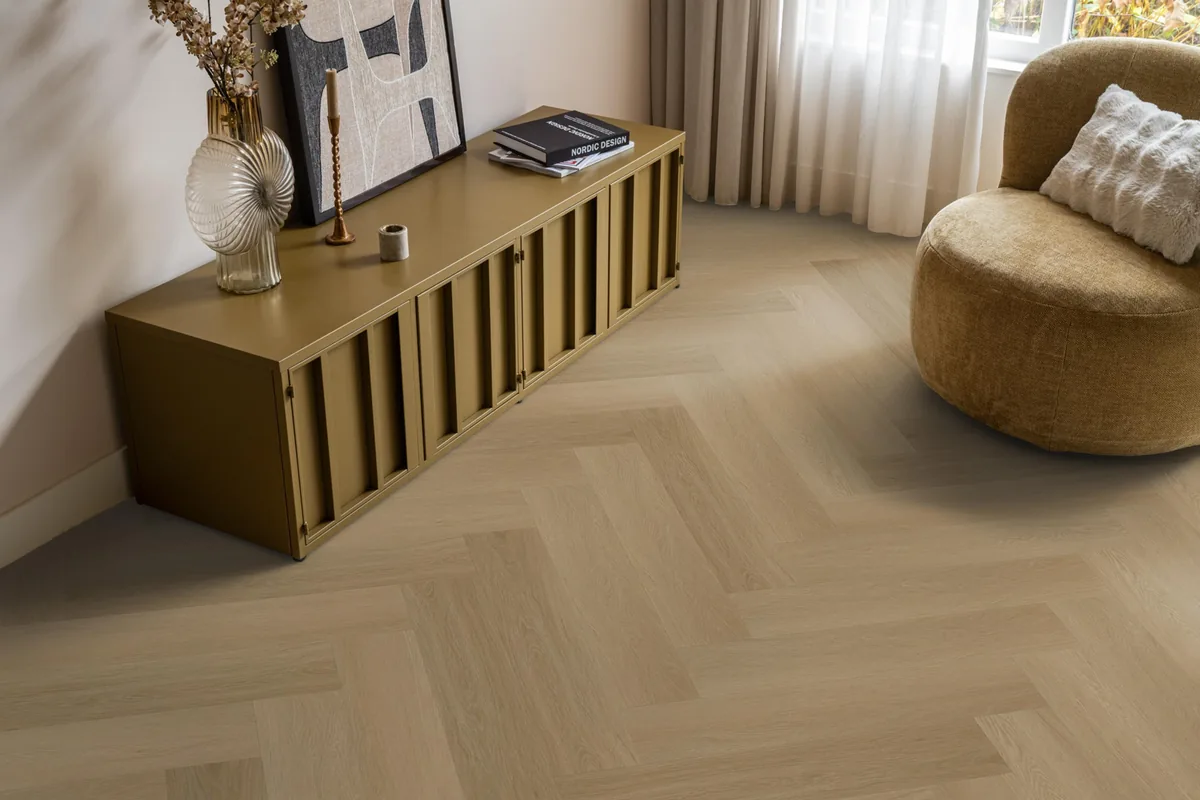 Fulham / Estino Warm oak, visgraat klik pvc in een woonkamer, met een okergeel dressoir en een ronde fauteuil