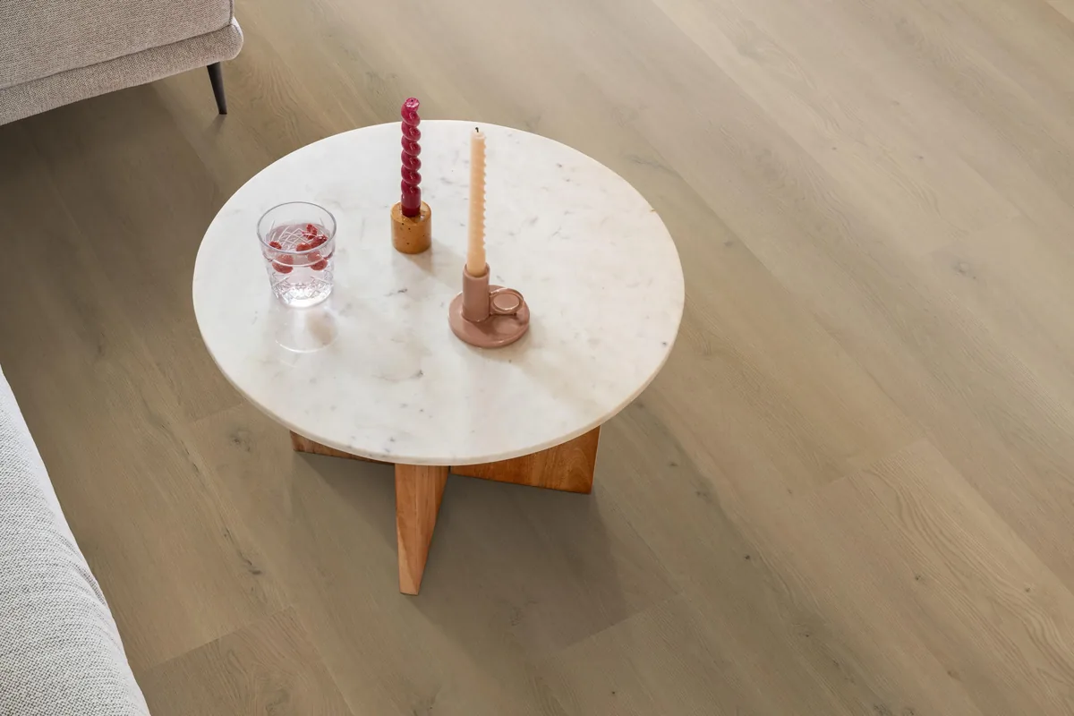 Greenwich / Espero warm oak, plak pvc in een woonkamer, met een ronde marmeren salontafel en twee kaarsen