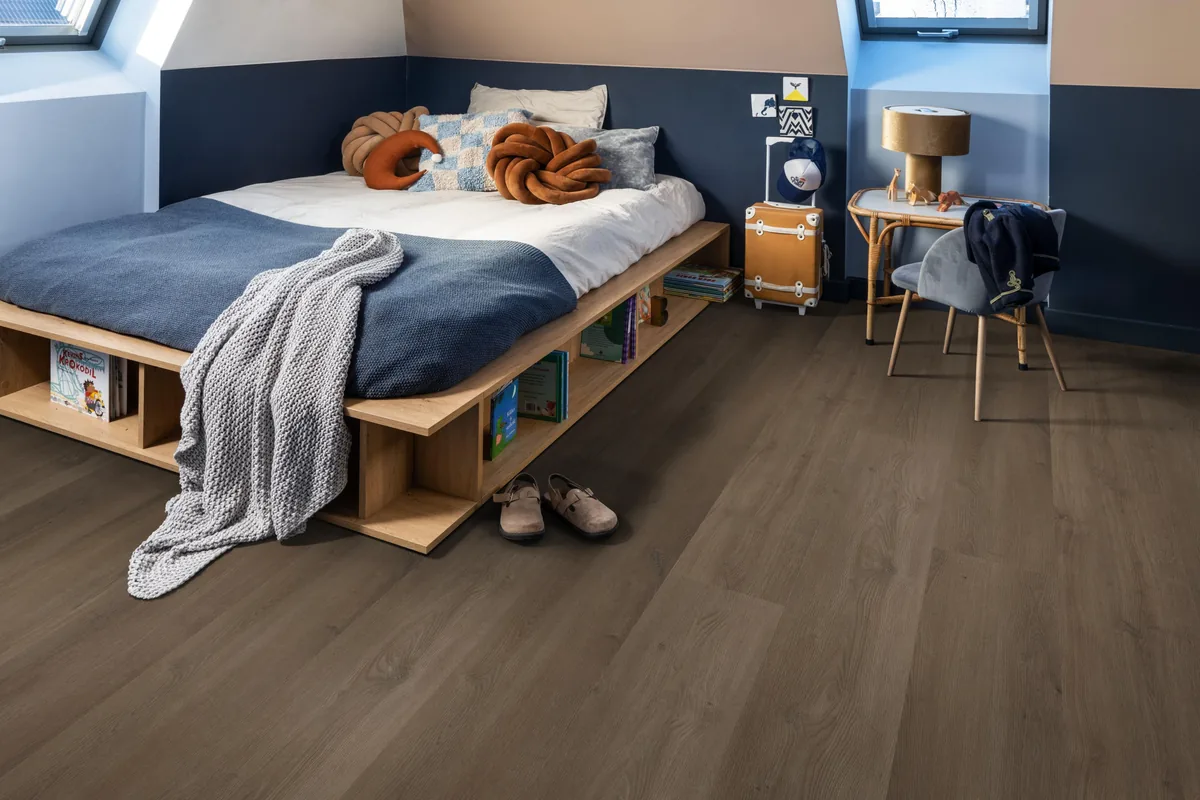 Greenwich / Espero warm brown, plak pvc in een slaapkamer onder een schuin dak, met een houten bedombouw en sloffen ervoor