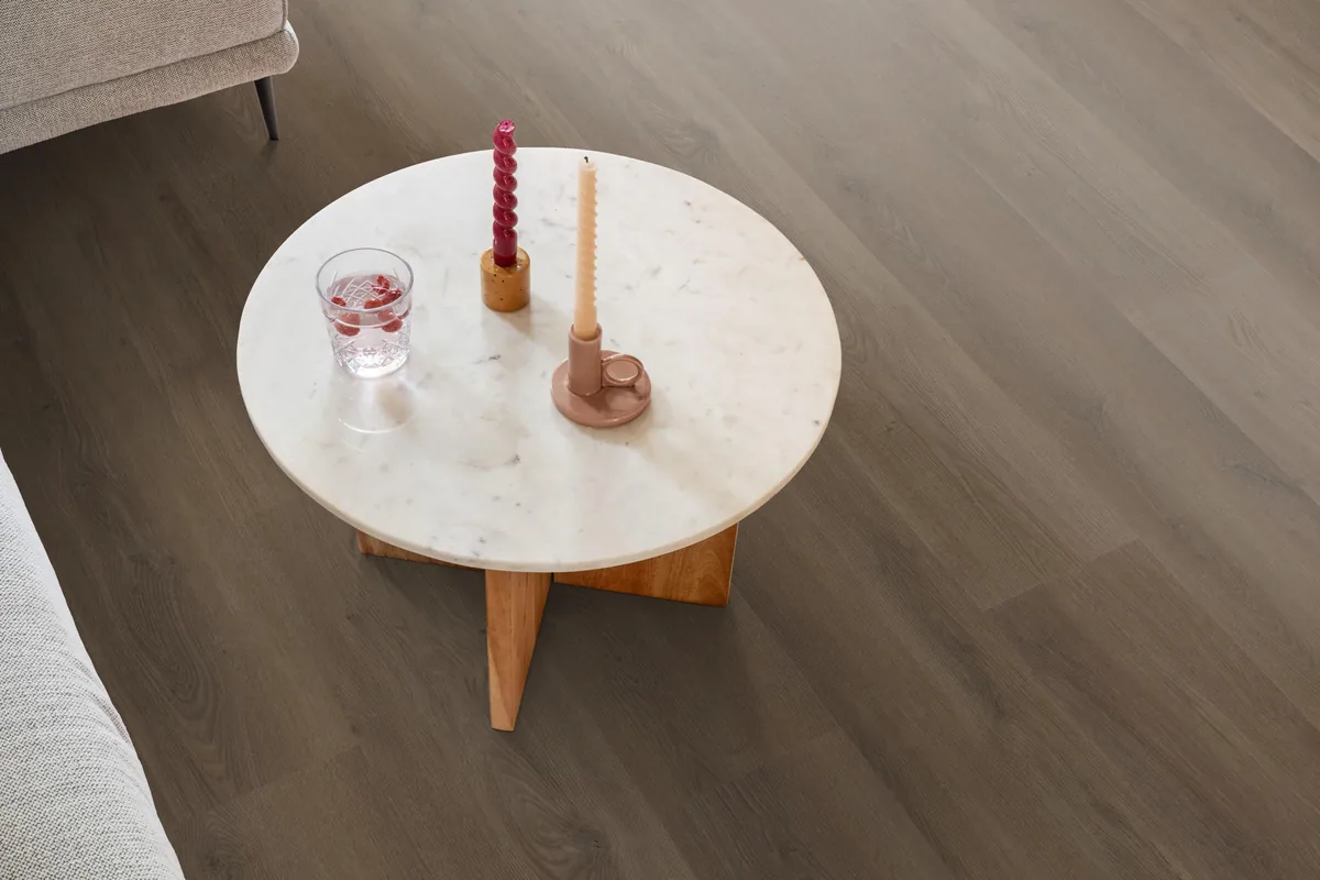 Greenwich / Espero warm brown, plak pvc in een woonkamer, met een ronde marmeren salontafel en twee kaarsen