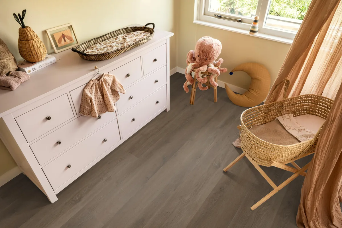 Greenwich / Espero warm brown, plak pvc in een babykamer, met een witte commode en een rieten wieg