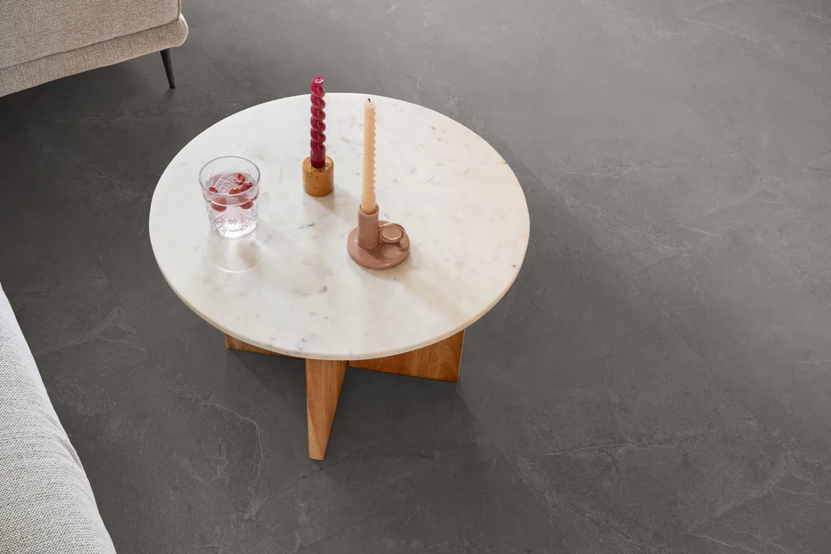 Stanmore / Noveno dark grey, plak pvc in een woonkamer, met een ronde marmeren salontafel en twee kaarsen
