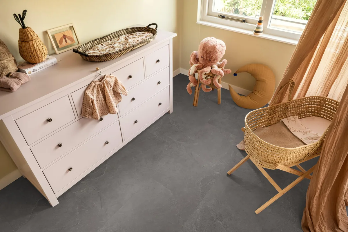 Stanmore / Noveno dark grey, plak pvc in een babykamer, met een witte commode en een rieten wieg
