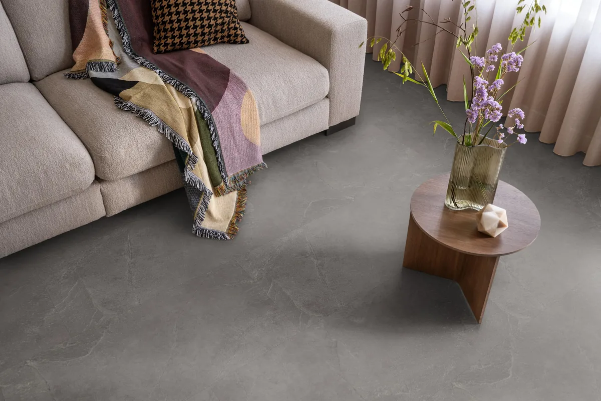 Stanmore / Noveno dark grey, plak pvc in een woonkamer, met een beige bank en een ronde bijzettafel met bloemen